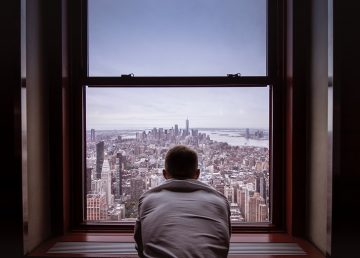 man looking out of window over cityscape