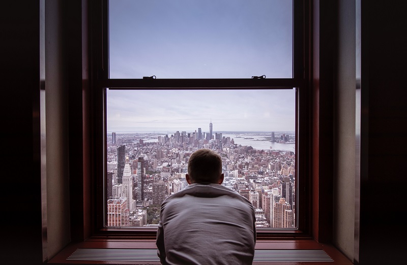 man looking out of window over cityscape